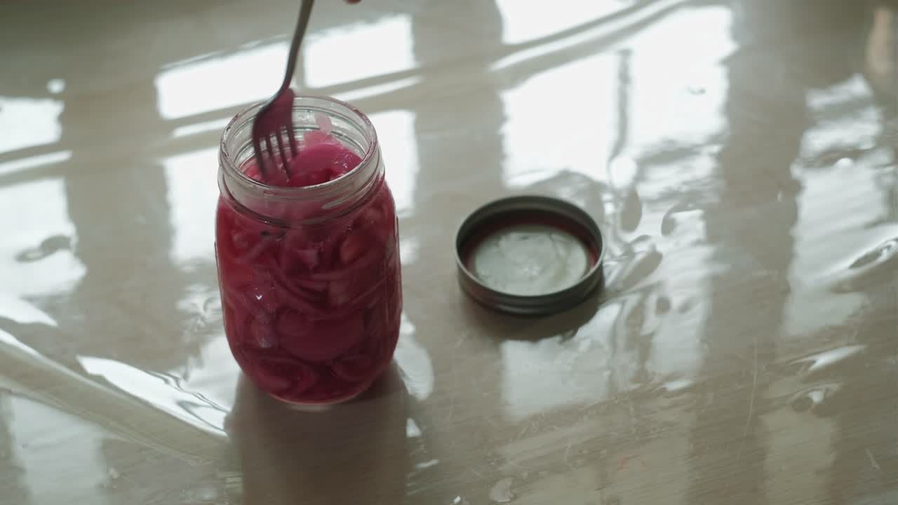 Close-up static shot of a mason jar filled with pickled red onions.