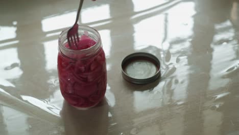 close-up static shot of a mason jar filled with pickled red onions.