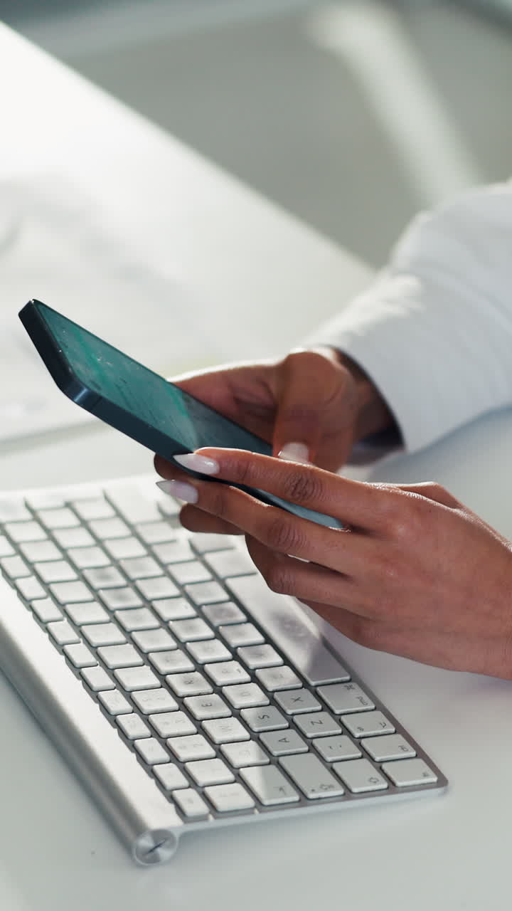 Primo piano di mani che usano uno smartphone accanto alla tastiera sulla scrivania