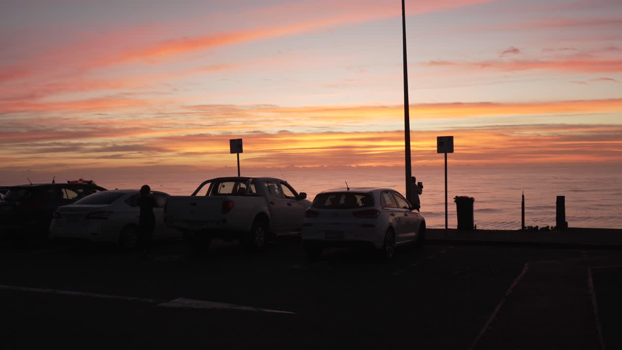 Parking spot at a cliffside near the beach with view on the ocean and orange sunrise horizon.