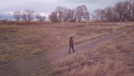 hombre caminando por un sendero en un campo frío e invernal