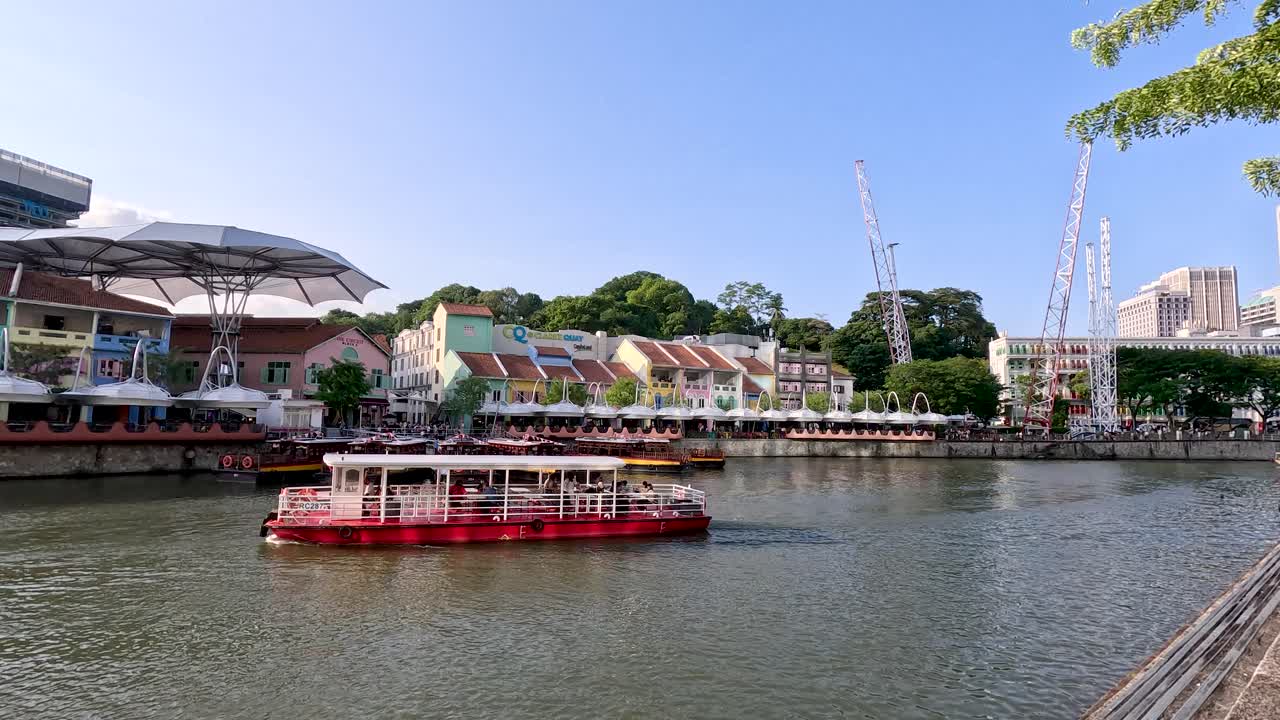 Tour boat glides along Singapore’s Clarke Quay riverfront, colorful buildings, clear daylight, steady camera