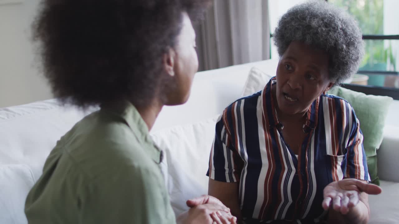 Afrikansk-amerikansk voksen datter og skuffet eldre mor i diskusjon hjemme, i sakte film.