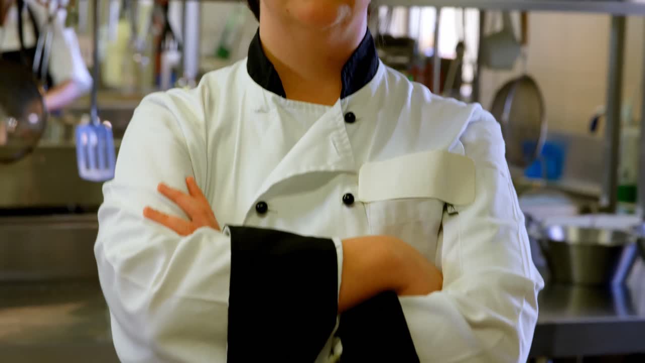 chef femenino de pie con los brazos cruzados en la cocina 4k