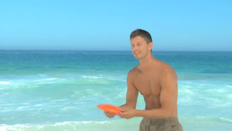 hombre guapo jugando al frisbee en la playa.