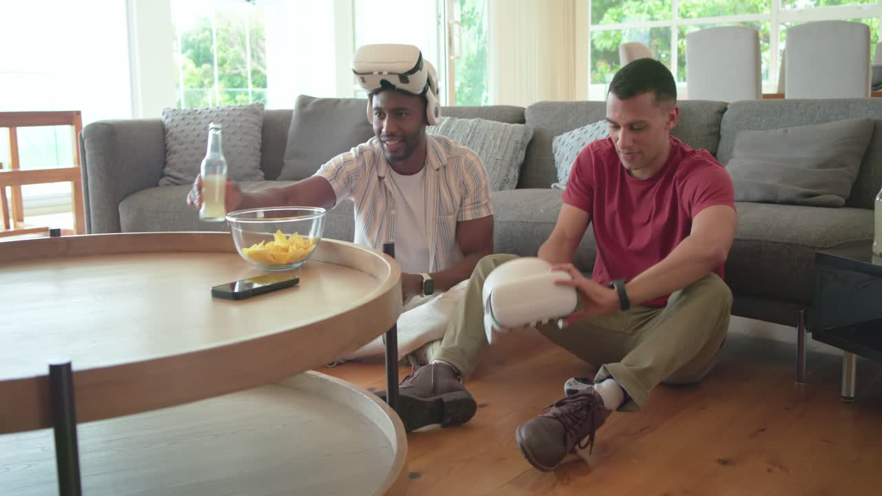 Diverse male friends putting on VR headsets at home gaming for fun then sharing lemonade toast