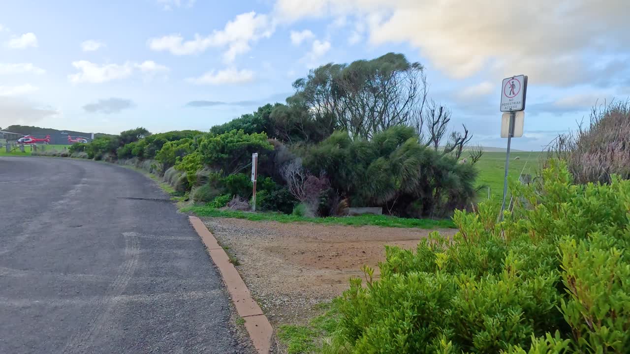 평화로운 도로변 장면이 펼쳐지고, 울창한 초록색과 밝은 하늘 아래의 개방된 을 보여줍니다.