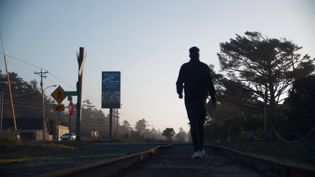 4k 슬로우 모션 영상으로 미국 오레곤주에 있는 오래된 미국 기차 트랙을 걷고 있는 거리 옆 - 하이킹 - 혼자 - 내향