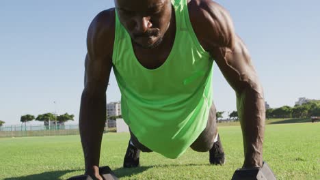 hombre afroamericano cansado haciendo ejercicio al aire libre haciendo abdominales y levantando pesas