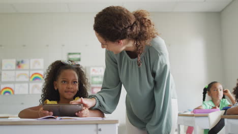 animation of back to school text against diverse female teacher teaching a girl in class at school