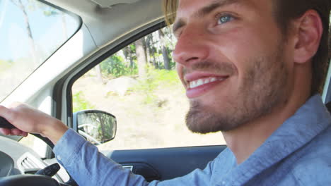 un joven sonriente conduciendo un coche en un viaje por carretera