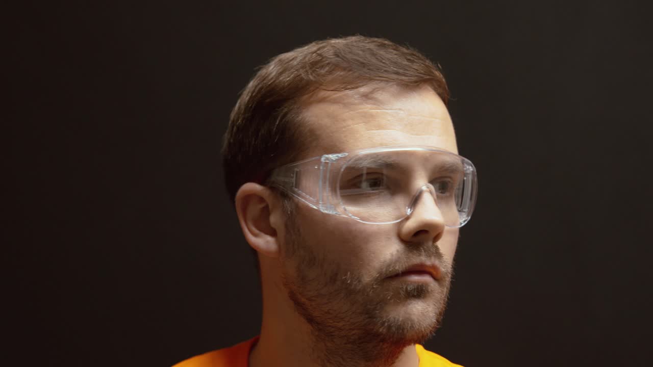 Close-up of a man putting on transparent safety goggles before starting work, emphasizing protection and workplace safety