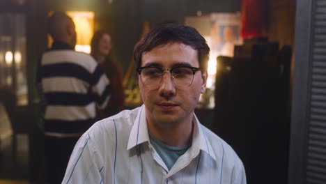 man looks around party uncomfortably, he talks to someone