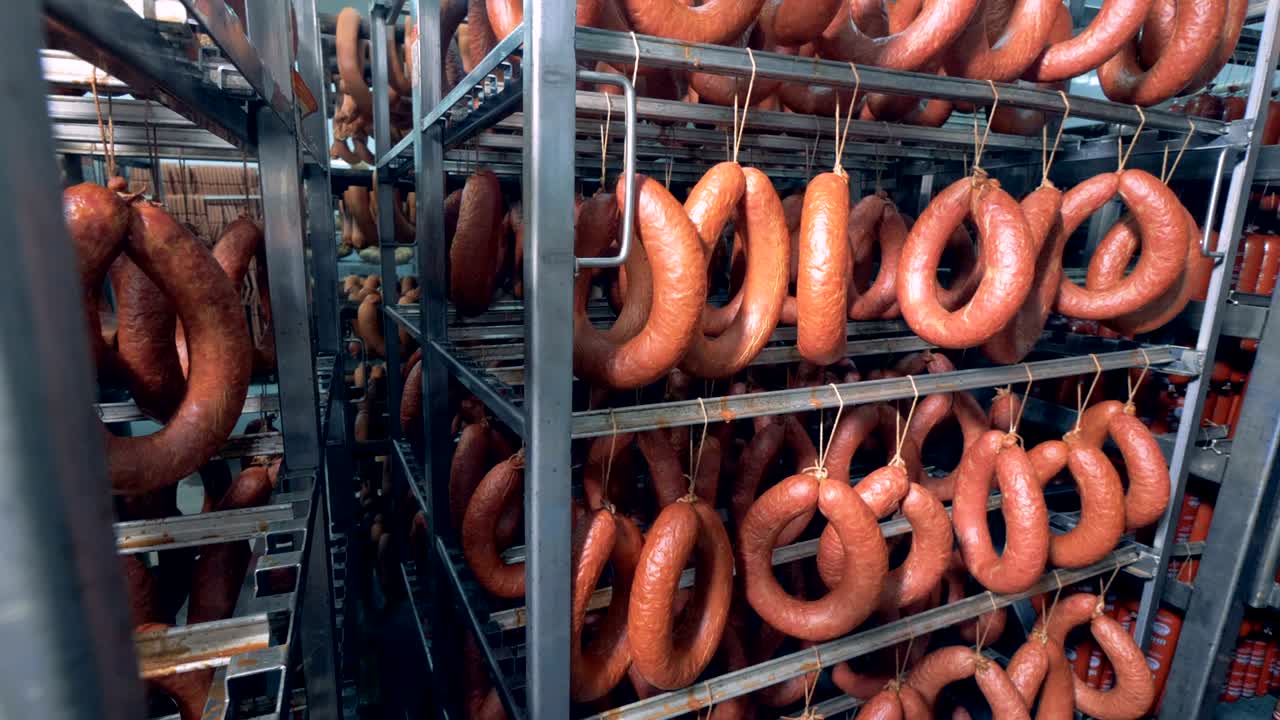 Salami, saucisses fumées, saucissons épais et fins sont exposés suspendus dans un entrepôt de viande