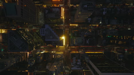 Aerial-birds-eye-overhead-top-down-panning-view-of-evening-traffic-in-city.-Fly-above-night-downtown-with-high-rise-buildings.-Manhattan,-New-York-City,-USA