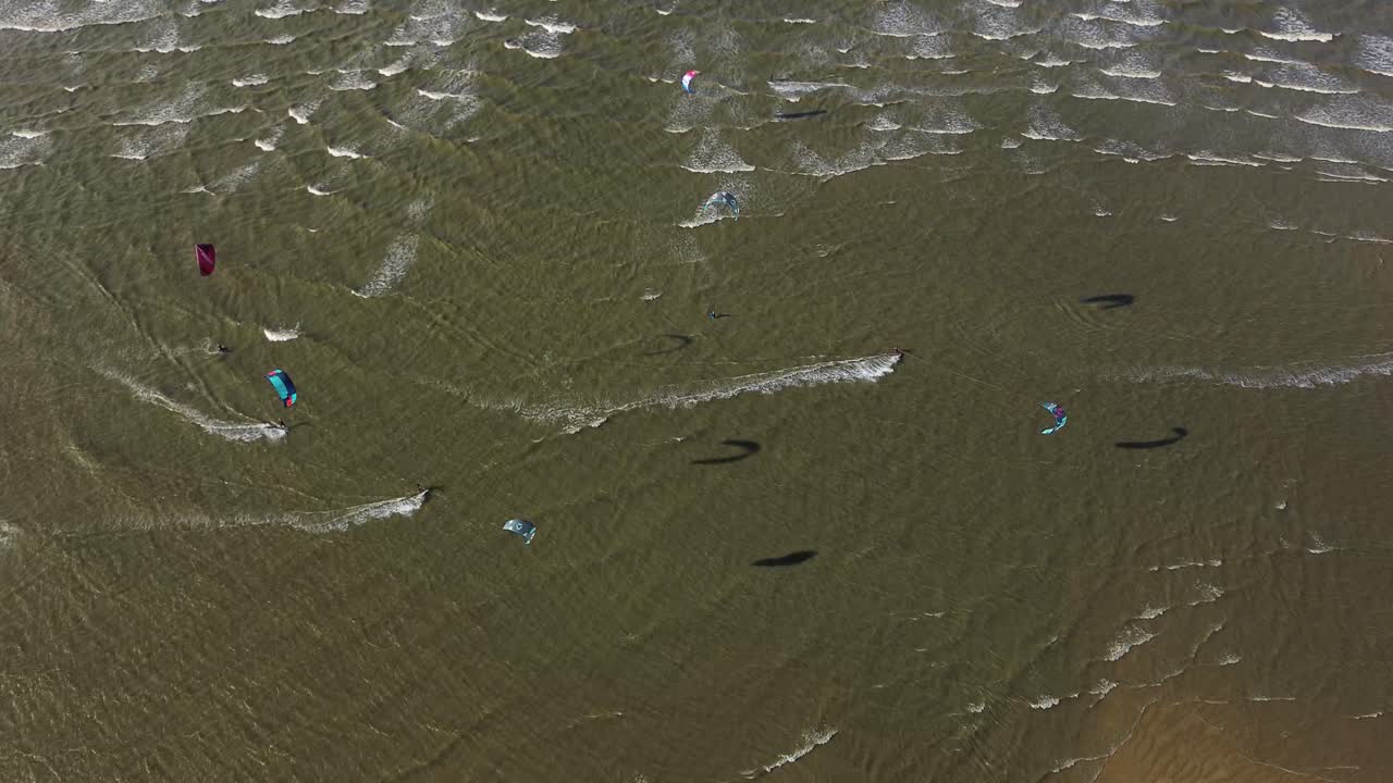 drone footage capturing people kitesurfing and flying kites along the wide sandy beaches of Normandy, France.