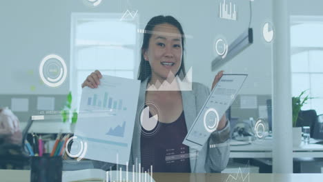 animation of digital business icons and data processing over biracial businesswoman in office