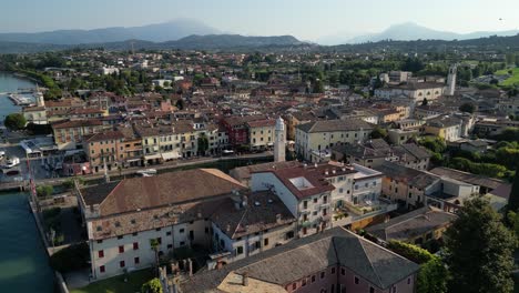 orbit movement revealing luxurious city with various different architectures style and colours placed by the shore with a massive mountains in the background hidden in clouds mysterious cinematic feel