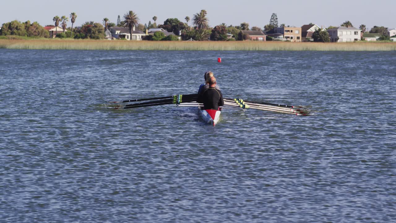 Four senior caucasian men and women rowing boat on a river