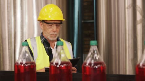 worker using digital tablet in bottle factory