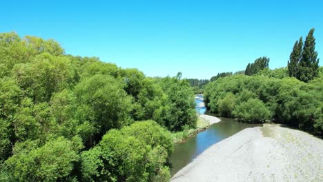 Aerial-descent-towards-beautiful-green-willow-trees-beside-Selwyn-River-at-Chamberlains-Ford-in-summertime