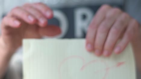 hands tearing paper with a drawn heart. love.