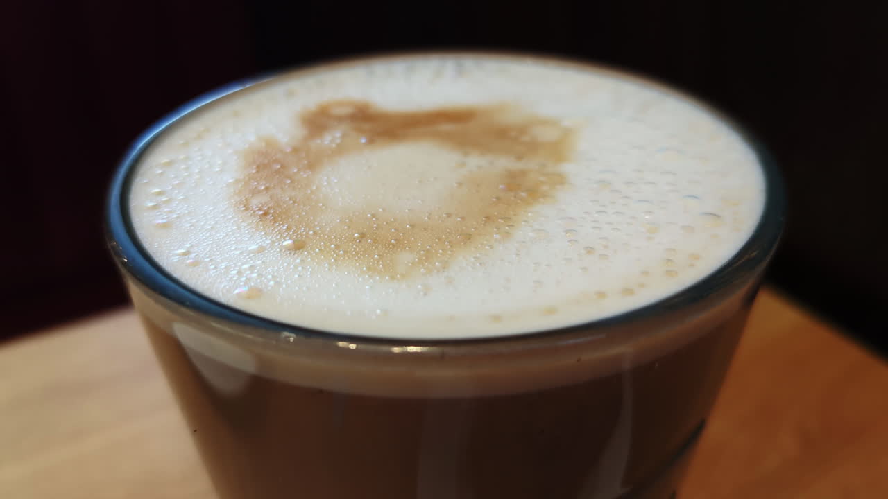 Latte Coffee Foam Close Up in Clear Glass with Details on Bubbles with Camera Slowly Panning.