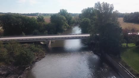 point of view slow drone flight of low altitude flight over a bridge crossing skunk river river running through rural iowa usa