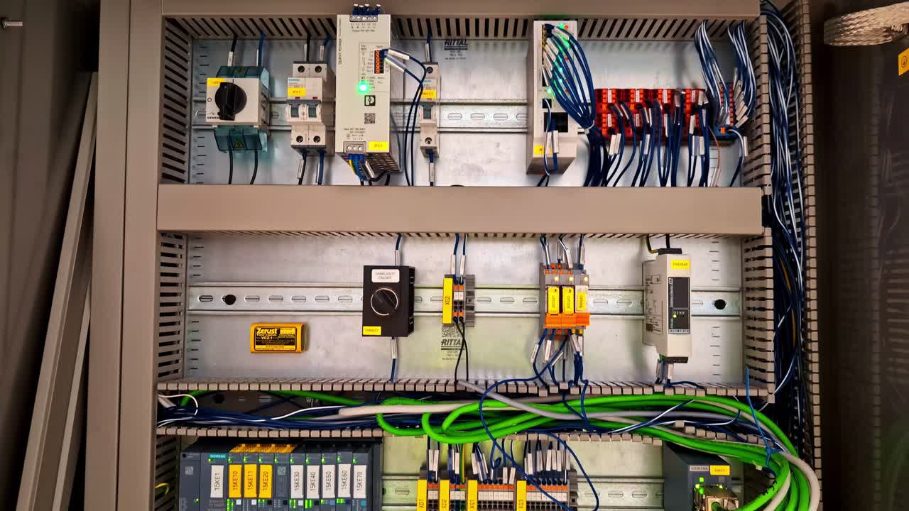 Closeup of electric circuit board inside control panel with labeled wires and components