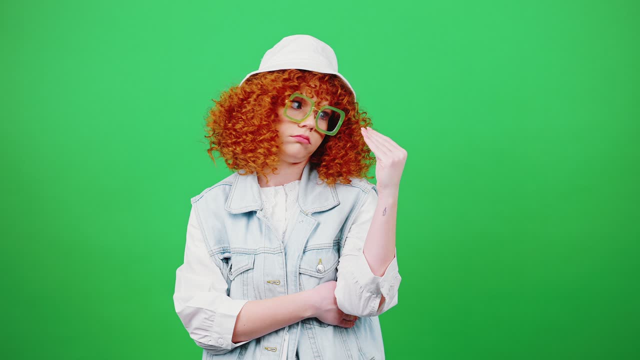 Empty talks concept. Young funny redhead woman in eyeglasses and panama hat showing blah blah gesture