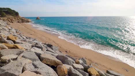 Hermosa-Playa-De-Arena-Mediterránea,-Maresme-Barcelona,-San-Pol-De-Mar,-Con-Rocas-Y-Mar-Tranquilo-Y-Turquesa