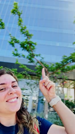 ambitious young woman points upwards in modern city