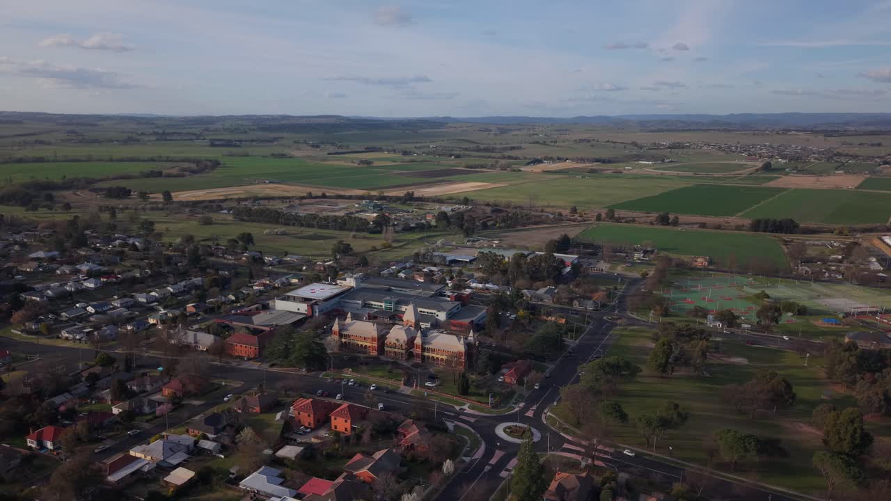 Ripresa aerea con drone che si allontana dal tetto dell'ospedale e dalle case vicine mentre il sole tramonta all'orizzonte; la luce calda che svanisce rivela i dettagli, Bathurst, Nuovo Galles del Sud, Australia