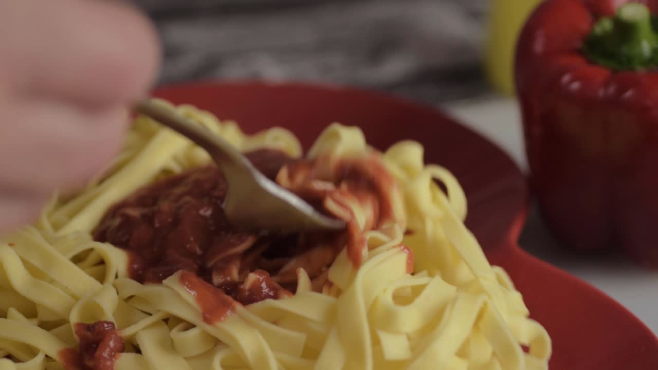 Eating tomato sauce over freshly cooked tagliatelle pasta medium shot