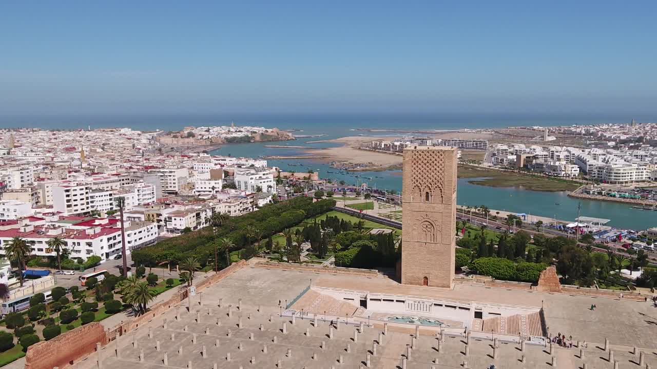 Detaljeret dronebillede af den historiske Hassan Tårn-minaret. Det fanger det indviklede stenarbejde, de gamle søjler nedenfor og en panoramaudsigt over Bou Regreg-floden, der møder Atlanterhavet.