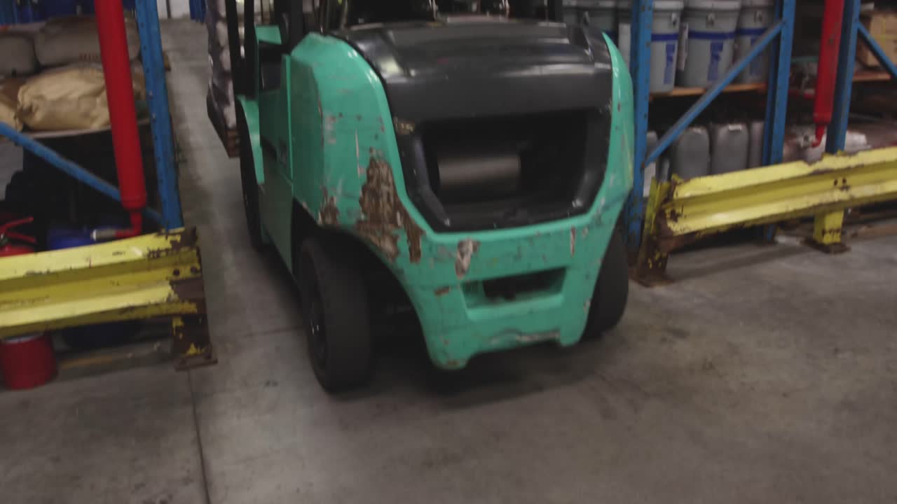 trabajador masculino conduciendo una carretilla elevadora en un almacén