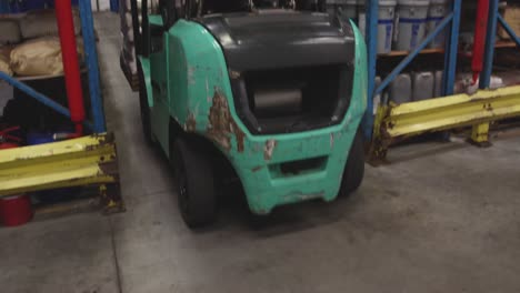 Male-worker-driving-forklift-in-a-warehouse