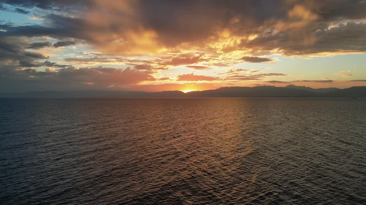 Smuk ildrød solnedgang over roligt hav, droneudsigt.