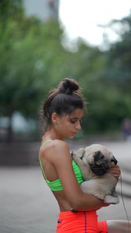 woman holding a pug puppy in a park