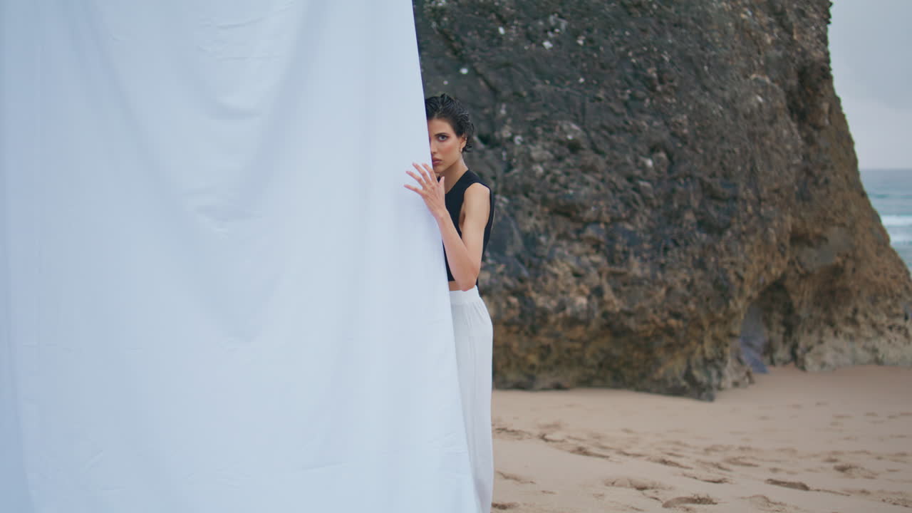 오션 클리프의 해변에서 스타일리시한 모델 촬영. 감각적인 패션 소녀 카메라를 찾고