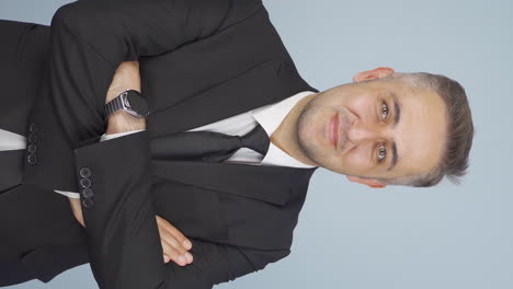 Vertical-video-of-Businessman-with-arms-folded-and-laughing-at-camera.