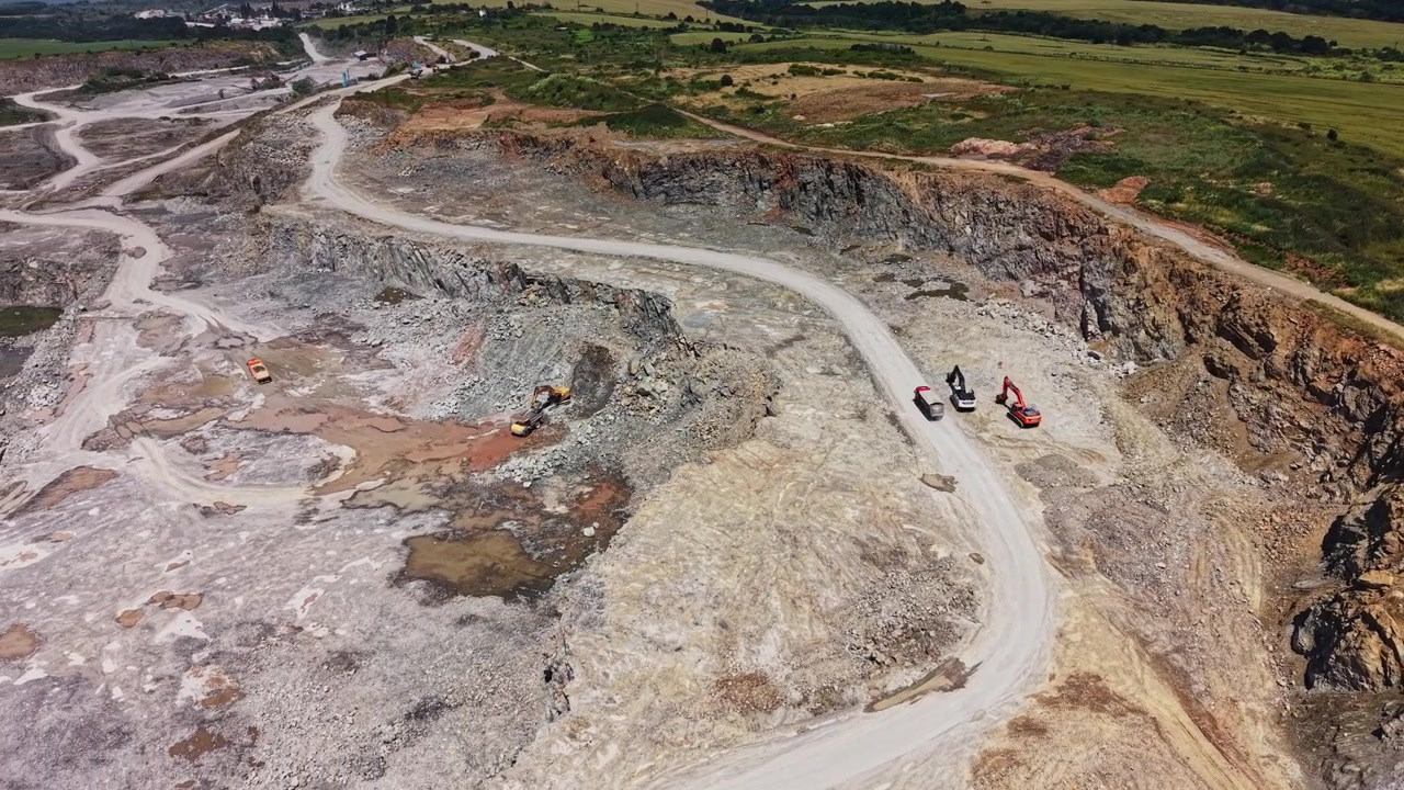 Heavy machinery works in an open quarry during daylight hours