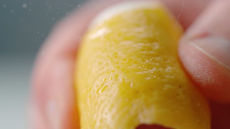 hand squeezing orange peel releasing essential oils