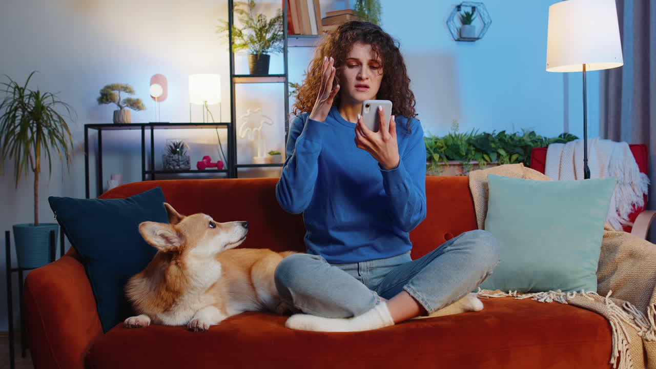 Upset displeased woman using smartphone sitting beside corgi dog loses lottery results or bad news