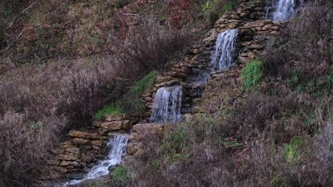 Pequeño-E-Idílico-Arroyo-En-Cascada-Rodeado-De-Un-Paisaje-De-Jardín-Marrón-Invernal-En-El-Parque-De-Jardín-De-La-Campiña-Inglesa-Rural