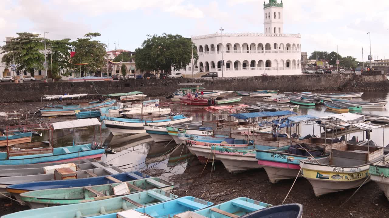 Colorful boats docked by a white historic building in Grande Comore, Comoros