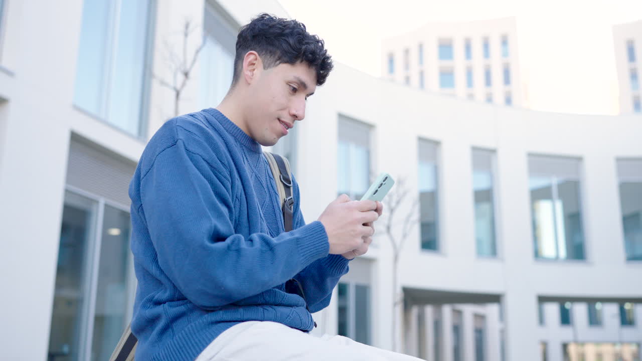 Young latin student using smartphone in university campus