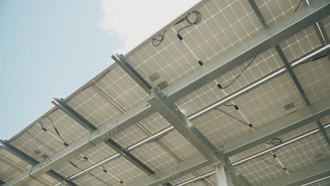 Bottom-up-shot-of-solar-panels-from-below-against-blue-sky-and-sun-outdoors,-close-up