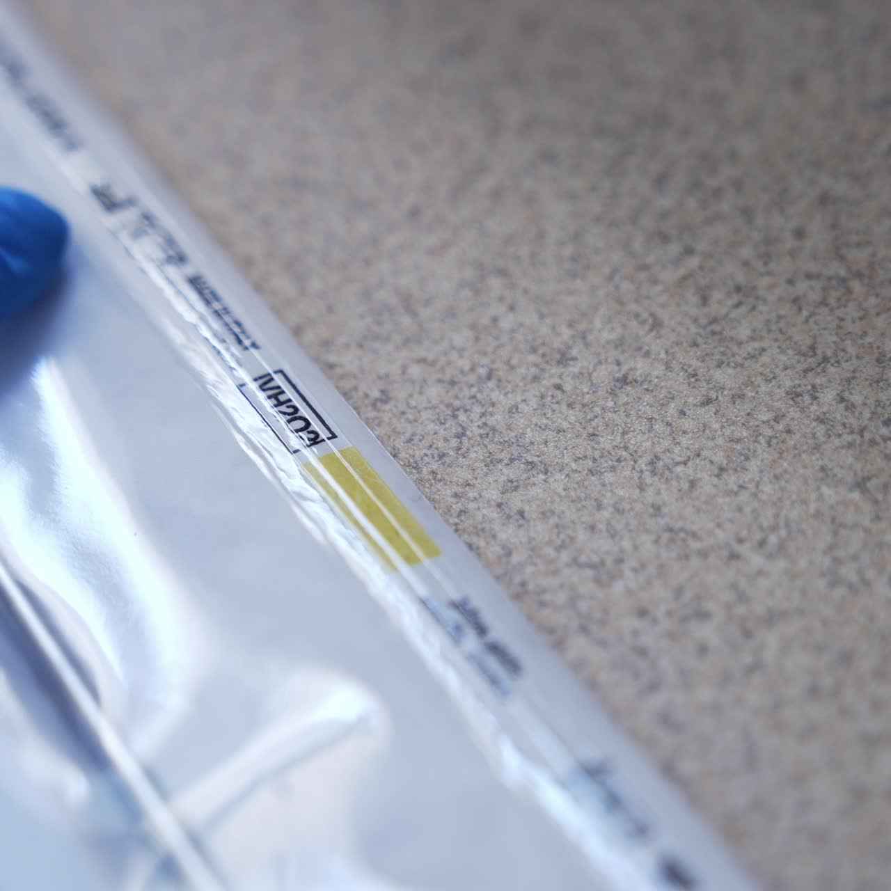 Metal tool packed into the plastic bag. Gloved hand of medic checks the vacuumed bag for integrity. Close up