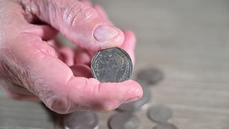 elderly hand holding a venezuelan bolivar coin from his country he left behind